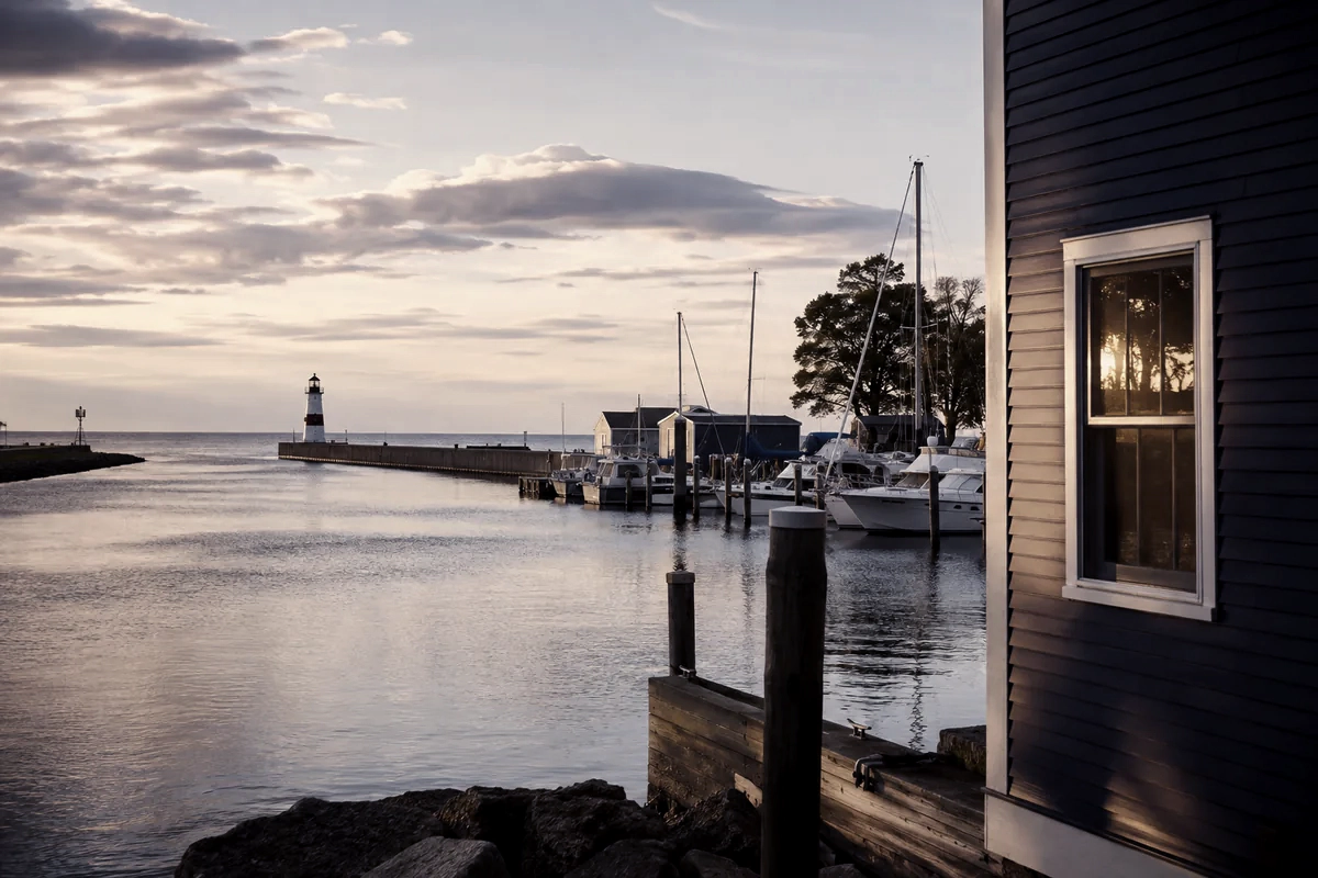 Illustration of Port Washington: moored sailboats and a harbor breakwater at dusk.